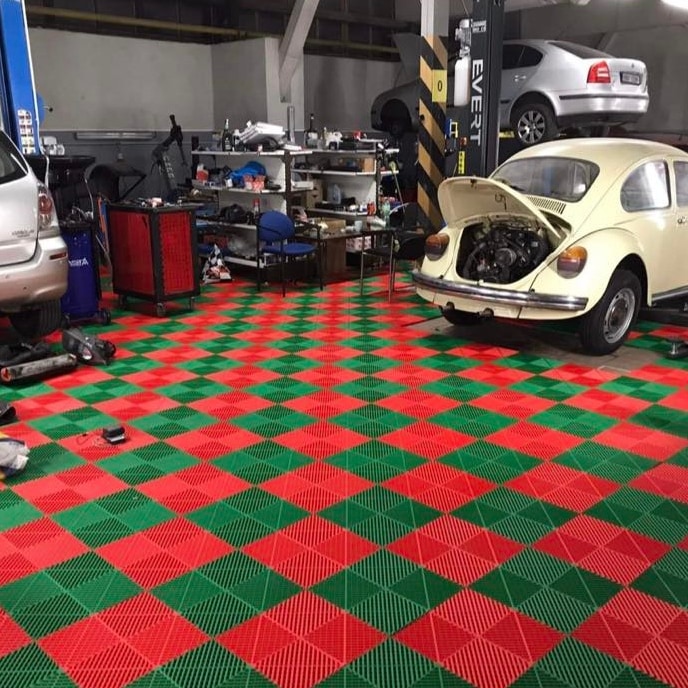 Červená a zelená šachovnice v dílně s automobilovými zvedáky.
